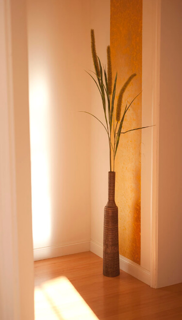 Ein Foto von einer schönen Vase vor orangenem Hintergrund in einem sonnigem Zimmereckchen.